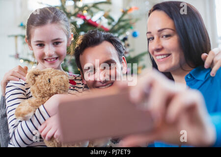 La famiglia felice con smart phone tenendo selfie in Natale soggiorno Foto Stock