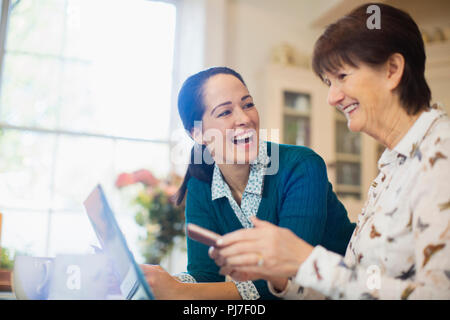 Felice figlia aiutando senior madre utilizzando laptop Foto Stock