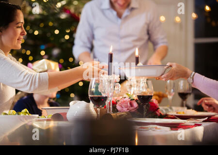 Famiglia passando il cibo, godendo di cena a lume di candela a cena di Natale Foto Stock