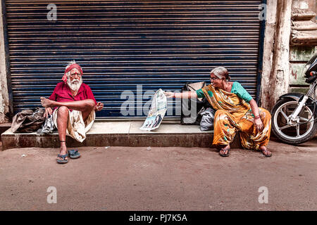 Senior Citizen donna leggendo il giornale e senior citizen uomo seduto vicino a. La foto è stata scattata in estate nella città di Ahmedabad Foto Stock