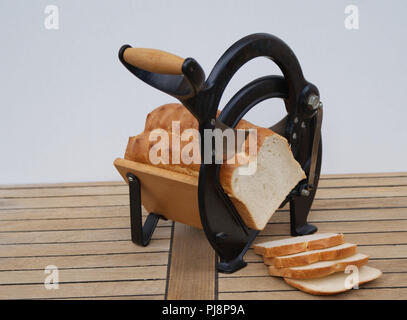 Vecchio danese affettatrice pane di legno su sfondo bianco con le fette di pane Foto Stock