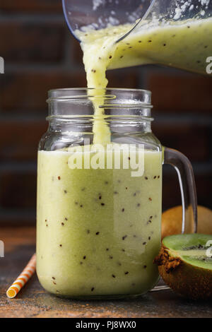 Processo di colata preparate di fresco frullati da kiwi in un vasetto di vetro Foto Stock