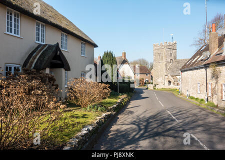 Dorchester, England, Regno Unito - 24 Febbraio 2018: il sole splende sul cottage tradizionale e la chiesa parrocchiale di West Stafford, vicino a Dorchester nel Dorset. Foto Stock