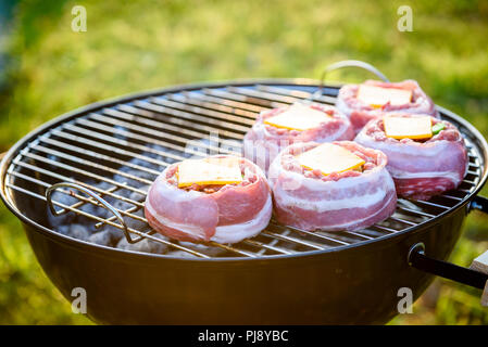 Rendendo fatta in casa birra può Bacon gli hamburger sul grill barbecue. La preparazione di polpette ripiene, avvolto in pancetta e grigliare sul calore indiretta nella natura a bac Foto Stock
