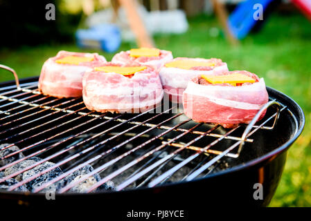 Rendendo fatta in casa birra può Bacon gli hamburger sul grill barbecue. La preparazione di polpette ripiene, avvolto in pancetta e grigliare sul calore indiretta nella natura a bac Foto Stock