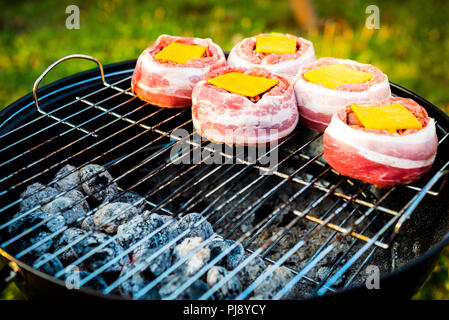 Rendendo fatta in casa birra può Bacon gli hamburger sul grill barbecue. La preparazione di polpette ripiene, avvolto in pancetta e grigliare sul calore indiretta nella natura a bac Foto Stock