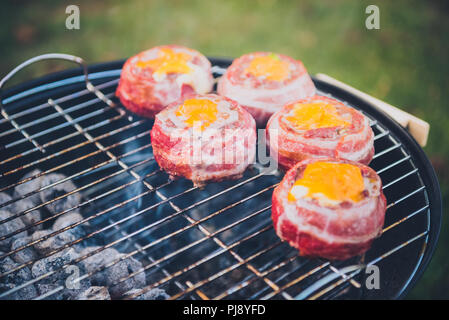 Rendendo fatta in casa birra può Bacon gli hamburger sul grill barbecue. La preparazione di polpette ripiene, avvolto in pancetta e grigliare sul calore indiretta nella natura a bac Foto Stock