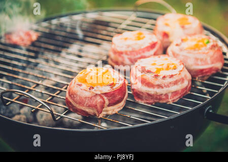 Rendendo fatta in casa birra può Bacon gli hamburger sul grill barbecue. La preparazione di polpette ripiene, avvolto in pancetta e grigliare sul calore indiretta nella natura a bac Foto Stock