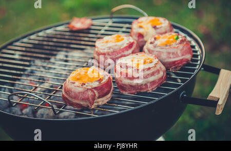 Rendendo fatta in casa birra può Bacon gli hamburger sul grill barbecue. La preparazione di polpette ripiene, avvolto in pancetta e grigliare sul calore indiretta nella natura a bac Foto Stock