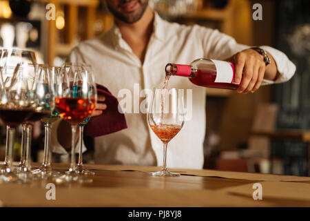 Vino rosato che viene versato nel bicchiere Foto Stock