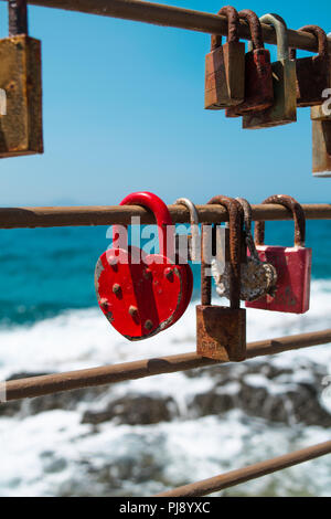 Amore Rosso blocca il lucchetto con lucchetti arrugginiti e mare in background Foto Stock