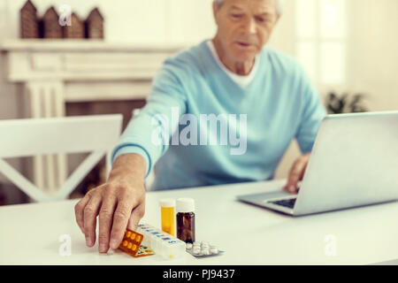 Senior gentleman prendendo il suo pillole a tavola Foto Stock