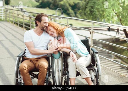 Amorevole moglie di ridere e abbracciando il marito Foto Stock