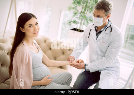 Bella donna incinta avente il suo impulso controllato Foto Stock