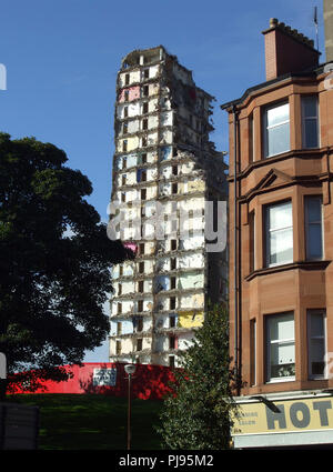 Un parzialmente demolito alto edificio di appartamenti in piedi accanto a una pietra arenaria rossa casamento in Glasgow. Foto Stock