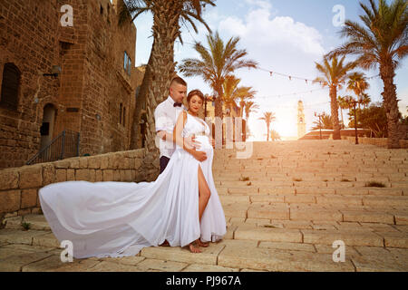 Felice e giovane coppia incinta abbracciando in olde city Foto Stock