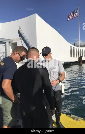 BASE COMUNE DI PEARL HARBOR-HICKAM - Royal Australian Navy Officer in miniera di carica l'eliminazione degli ordigni esplosivi, Chief Petty Officer Ciad Buhlmann (destra), discute l'immersione sulla USS Arizona con un membro della United States Coast Guard (sinistra) e un gioco australiano subacqueo durante RIMPAC 2018. Venticinque nazioni, 46 navi, cinque sommergibili, circa 200 aerei, e 25.000 personale partecipano RIMPAC dal 27 giugno al 2 agosto in e intorno alle Isole Hawaii e la California del Sud. Il più grande del mondo marittimo internazionale esercitazione RIMPAC offre una singolare opportunità di formazione mentre fo Foto Stock