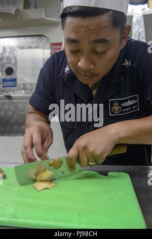 Mare del Giappone (Luglio 8, 2018) specialista culinaria 2a classe Robert Rey, da San Jose, California, prepara piatti della cucina di bordo dell'Ticonderoga-class guidato-missili cruiser USS Antietam (CG 54). Antietam è di pattuglia NEGLI STATI UNITI 7 flotta area di operazione il supporto di sicurezza e stabilità nella regione Indo-Pacifico. Foto Stock