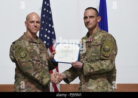 Col. Scott Gibson, 407 Aria Gruppo Expeditionary commander e presiedere officer, presenta il servizio meritevole medaglia di Lt. Col. Michael settimane durante un cambiamento di cerimonia di comando in una località segreta nel sud-ovest Asia Luglio 8, 2018. Settimane rinunciato il comando del 407 forza expeditionary squadrone di supporto di Lt. Col. Lynn Lightfoot. Foto Stock