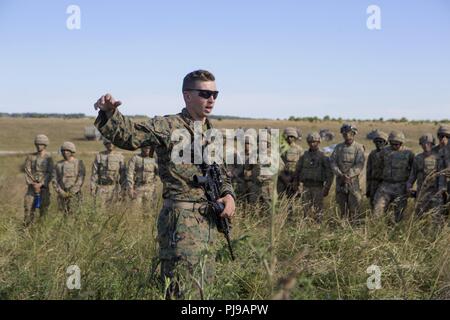 Stati Uniti Marine Corps 1Lt. Zachary Liskay, il delegato di Echo in batteria, 2° Battaglione, decimo reggimento Marine (2/10), seconda divisione Marine, parla con esercito britannico soldati assegnato al primo cavallo Royal Artillery a Salisbury, Inghilterra, 2 luglio 2018. Marines con l'unità condotta live-fire esercizi usando M777 Obice durante l'esercizio cannone verde 18. Cannone verde è una multinazionale esercizio fornendo U.S. Marines le opportunità di scambio di tattiche e tecniche nonché al progetto letalità e la potenza di combattimento in tutto il mondo al fianco di nazioni partner. Foto Stock