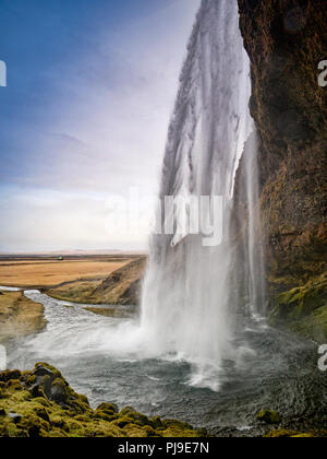 22 Aprile 2018: Sud Islanda - Seljalandsfoss cascata. Due persone possono solo essere veduto camminare sulla roccia dietro la cascata. Foto Stock