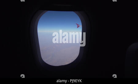 La gamma della montagna dalla finestra di aereo. Ala di aeroplano. Vista aerea su montagne attraverso la finestra di un aeromobile. In Montagna a partire dalla finestra di aereo. Concetto di viaggio. Foto Stock