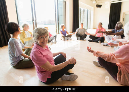 Ritratto sorridente senior attiva donna meditando in cerchio Foto Stock