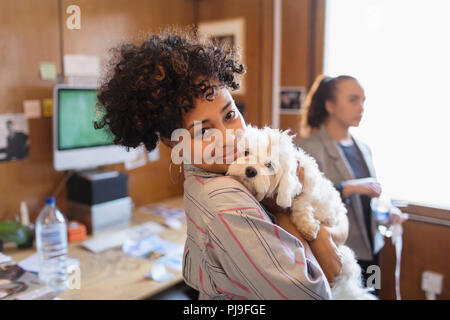 Ritratto sorridente imprenditrice creativa con cute cane in ufficio Foto Stock