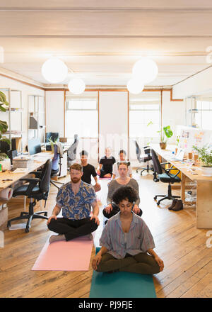 Serena azienda creativa persone meditando in ufficio Foto Stock