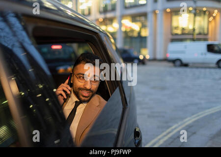 Imprenditore parlando su smart phone in taxi crowdsourced Foto Stock