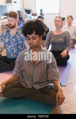 Serena azienda creativa persone meditando in ufficio Foto Stock