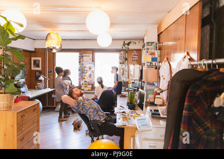 Creative designer maschio stretching, cercando in office Foto Stock
