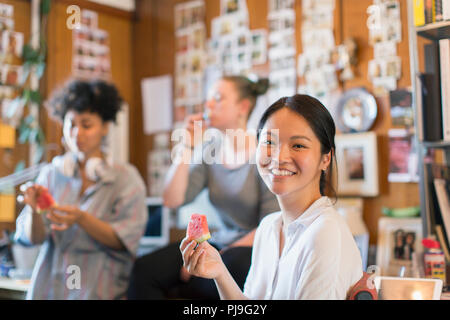 Ritratto sorridente imprenditrice creativa mangiando anguria in office Foto Stock