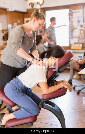 Creative imprenditrice ricevere massaggi da massaggiatrice in office Foto Stock
