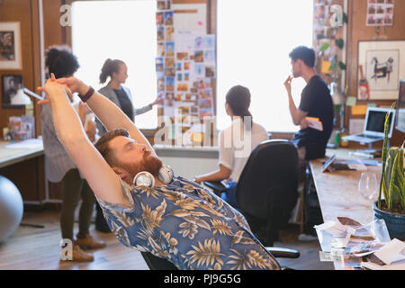 Creative designer maschio stretching in ufficio Foto Stock