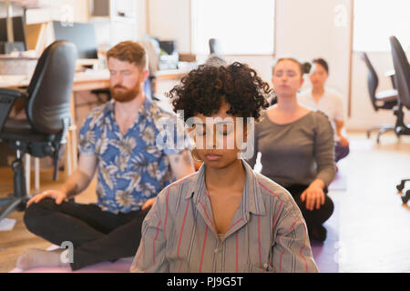 Serena azienda creativa persone meditando in ufficio Foto Stock