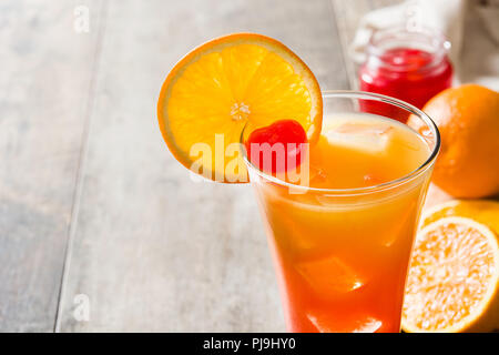 Tequila Sunrise cocktail in vetro su un tavolo di legno. Copyspace Foto Stock