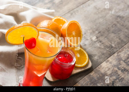 Tequila Sunrise cocktail in vetro su un tavolo di legno. Copyspace Foto Stock