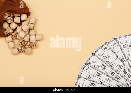 Lotto in legno Barili con borsa marrone e carte da gioco su sfondo beige. Gioco di bordo del lotto. Vista da sopra con lo spazio di copia Foto Stock