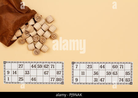 Lotto in legno Barili con apri Borsa marrone e carte da gioco su sfondo beige. Gioco di bordo del lotto. Vista da sopra con lo spazio di copia Foto Stock