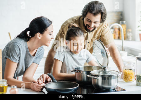 Sorridente giovane famiglia la cucina insieme in cucina Foto Stock