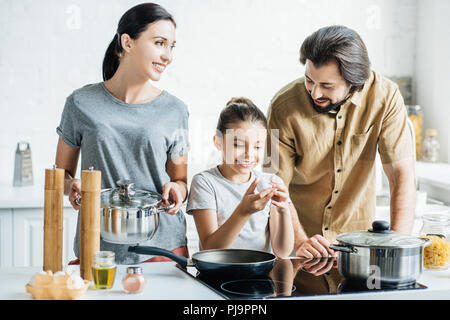 Famiglia sorridente con piccola figlia frittata di cottura in cucina Foto Stock