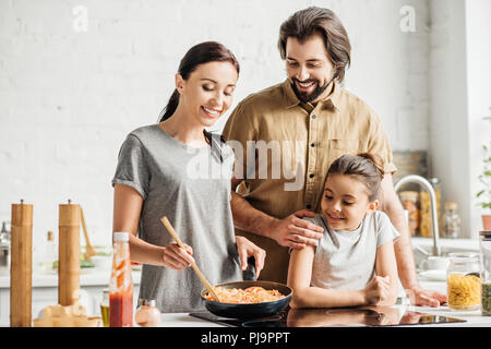 Bella famiglia con piccola figlia frittata di cottura in cucina Foto Stock