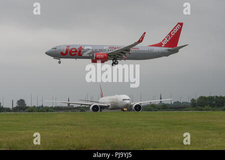 Jet2 vacanze volo che arriva mentre Emirates vi attende in partenza dall'Aeroporto Internazionale di Glasgow, Renfrewshire, Scozia. Foto Stock