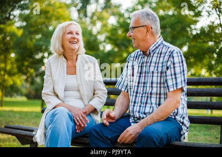 Due felici gli anziani sono seduti e parlare nel parco. Foto Stock