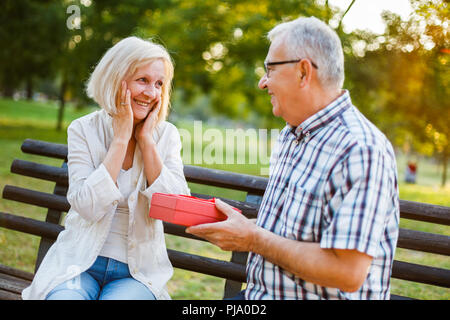 Donna Senior è lieta con regalo dal suo uomo. Foto Stock