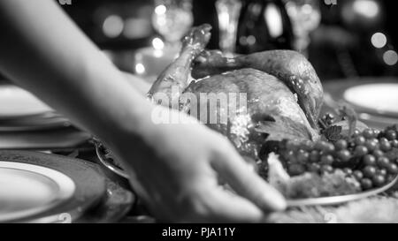 Primo piano immagine della giovane donna di mettere il pollo al forno sul tavolo da pranzo servito per cena di Natale Foto Stock