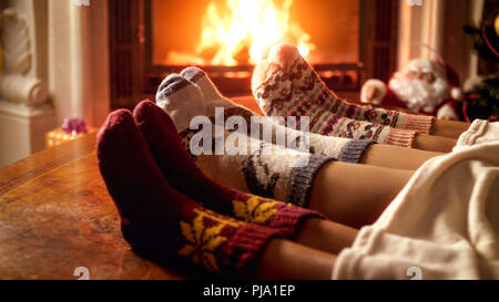 Famiglia nel caldo Calze a maglia sdraiato sul divano accanto al caminetto Foto Stock