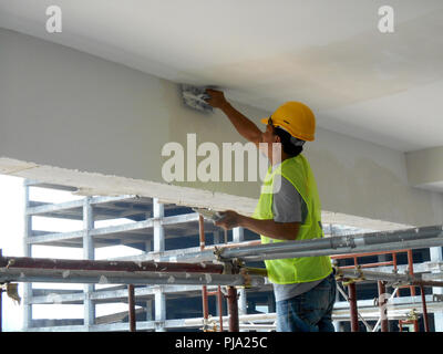 Sito in costruzione i lavoratori stanno facendo intradosso soffitto foglietta lavoro presso il sito di costruzione. Base e finale dello strato di rivestimento di applicare per ottenere la superficie liscia. Foto Stock