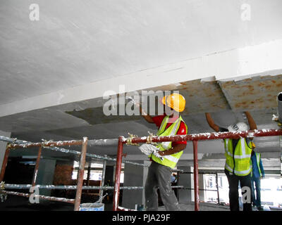 Sito in costruzione i lavoratori stanno facendo intradosso soffitto foglietta lavoro presso il sito di costruzione. Base e finale dello strato di rivestimento di applicare per ottenere la superficie liscia. Foto Stock